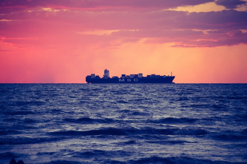 black ship on calm sea during golden hour